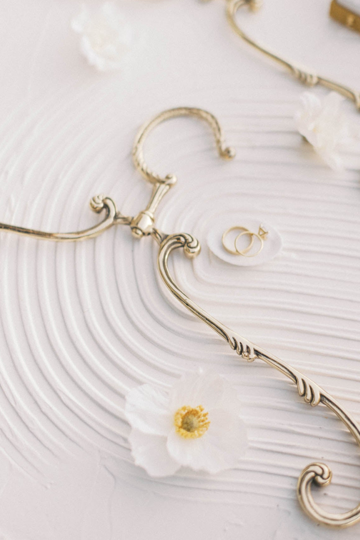Gold-tone vintage swivel hanger on textured white with a flower