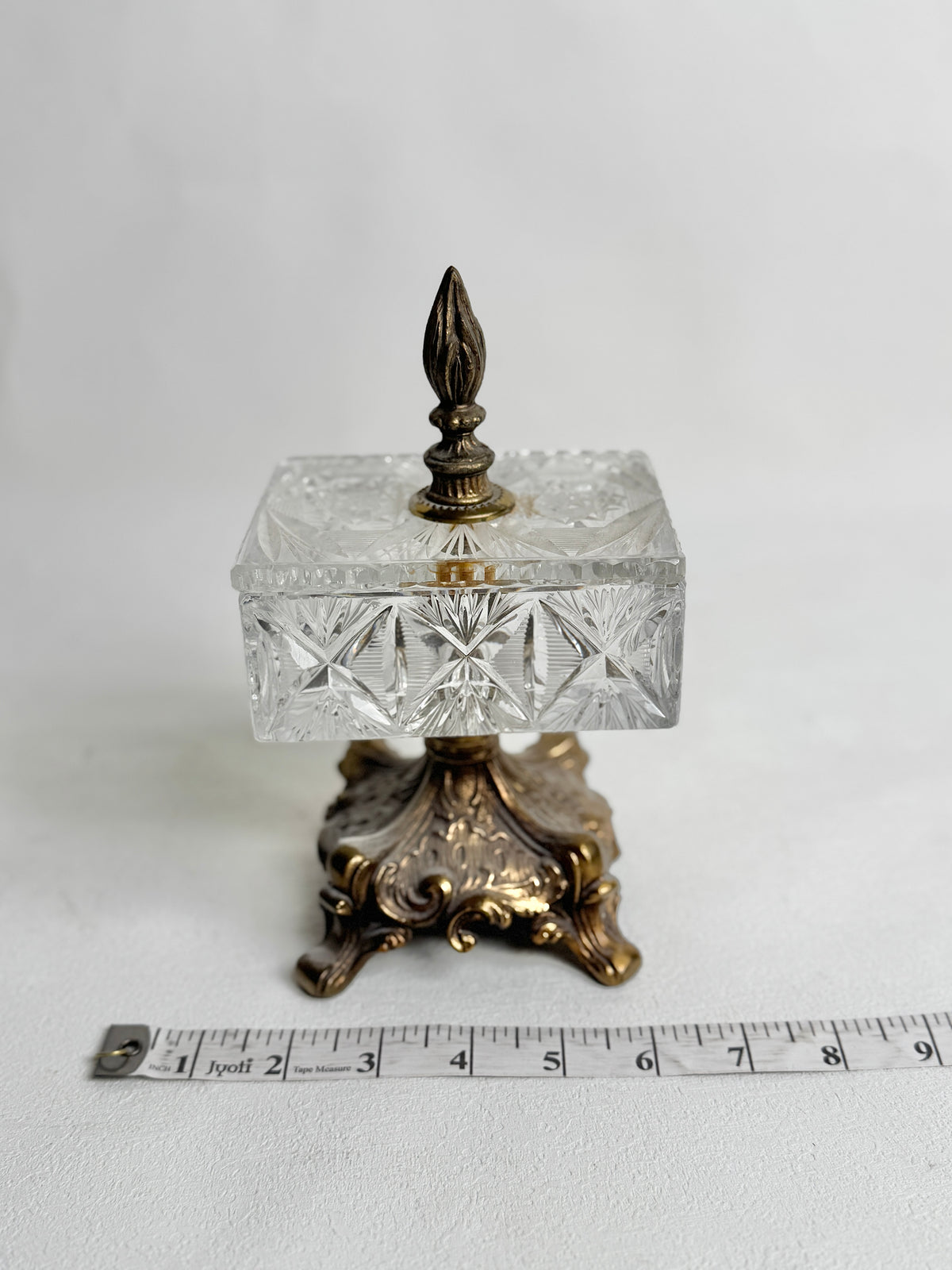 Vintage crystal pedestal box with a tape measure showing its width