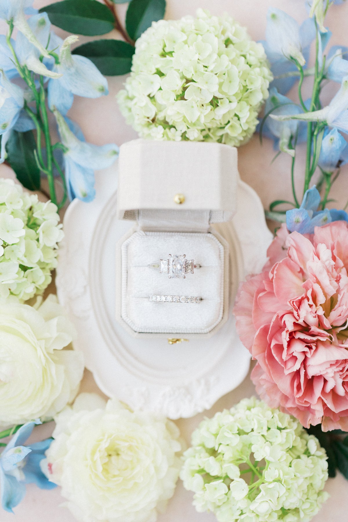 Dove white Radiant Legacy ring box on an ornate plate with hydrangeas and roses