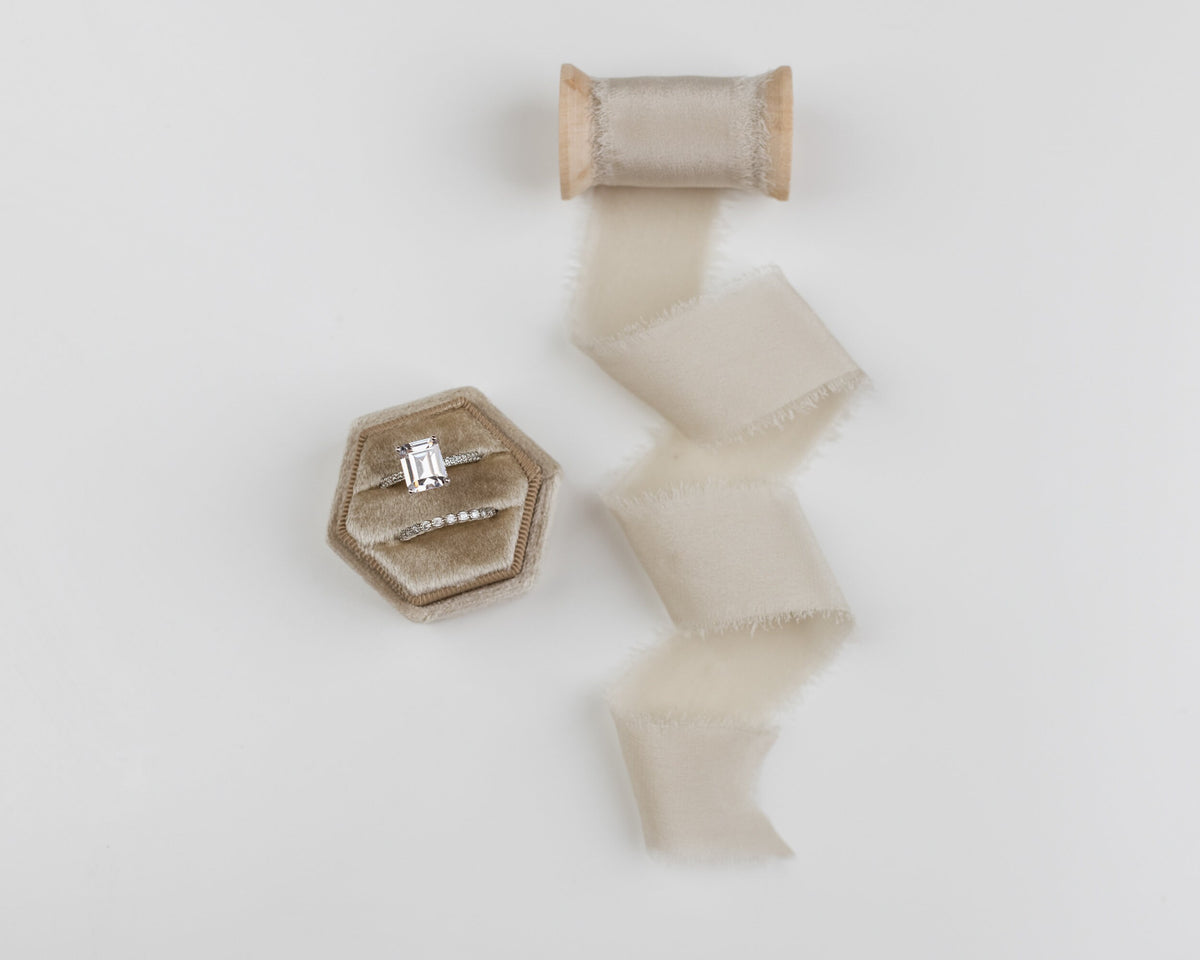 Fawn silk ribbon on a spool beside a linen ring box