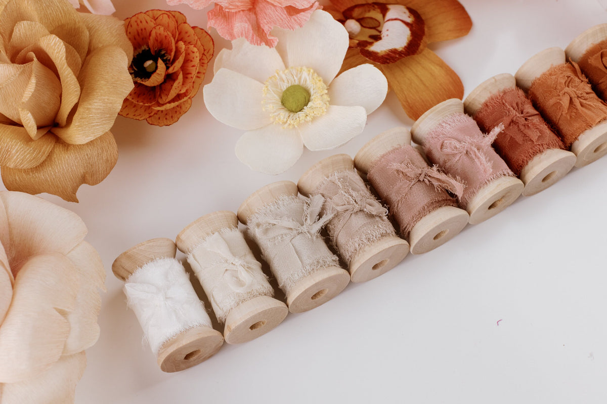 Row of silk ribbon spools in muted tones with florals