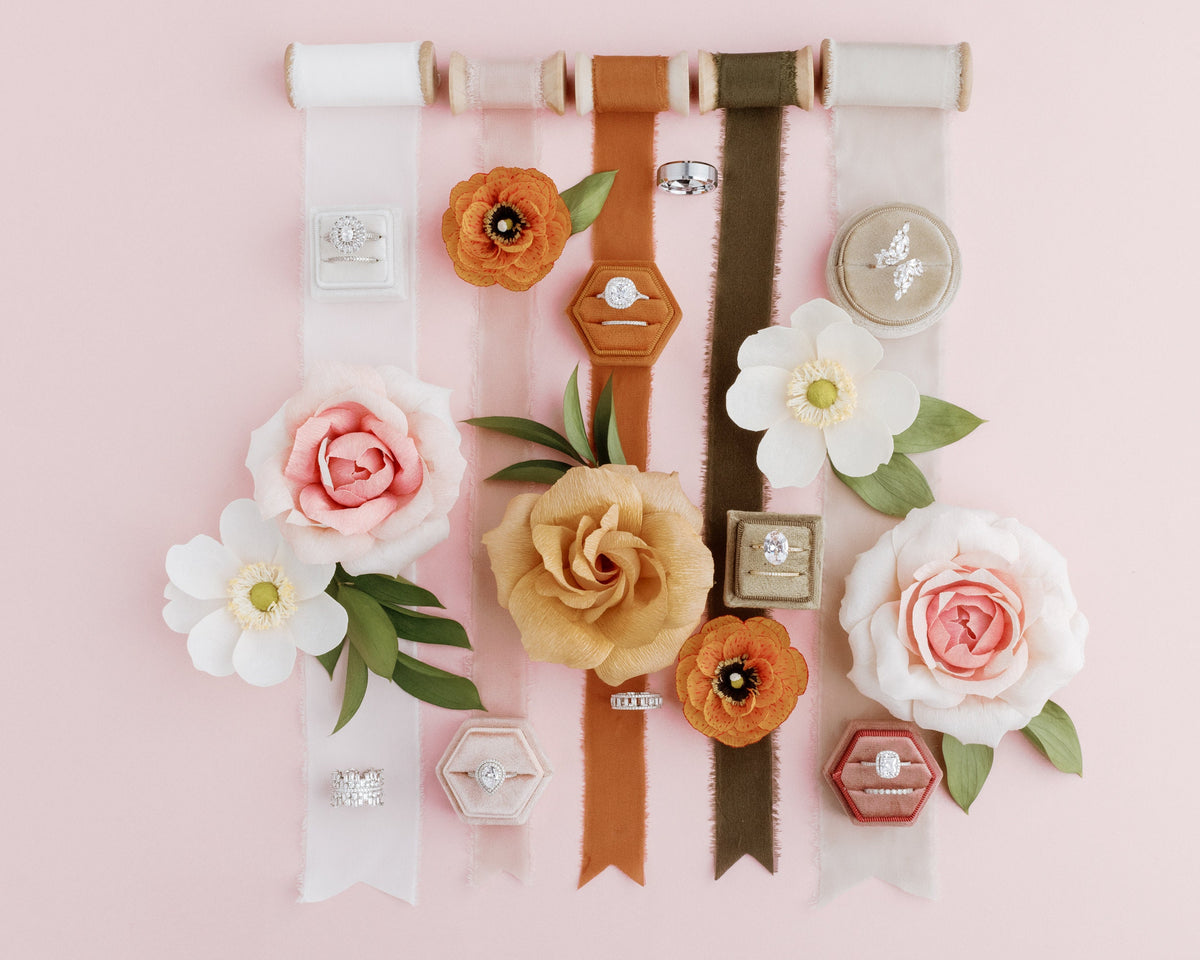 Silk ribbons in several colors laid out with paper flowers on blush