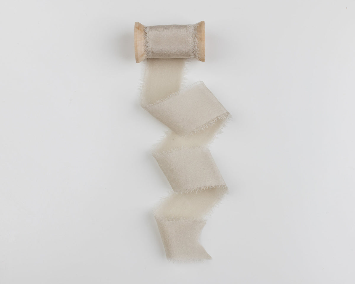 Fawn taupe silk ribbon unwound from a wooden spool