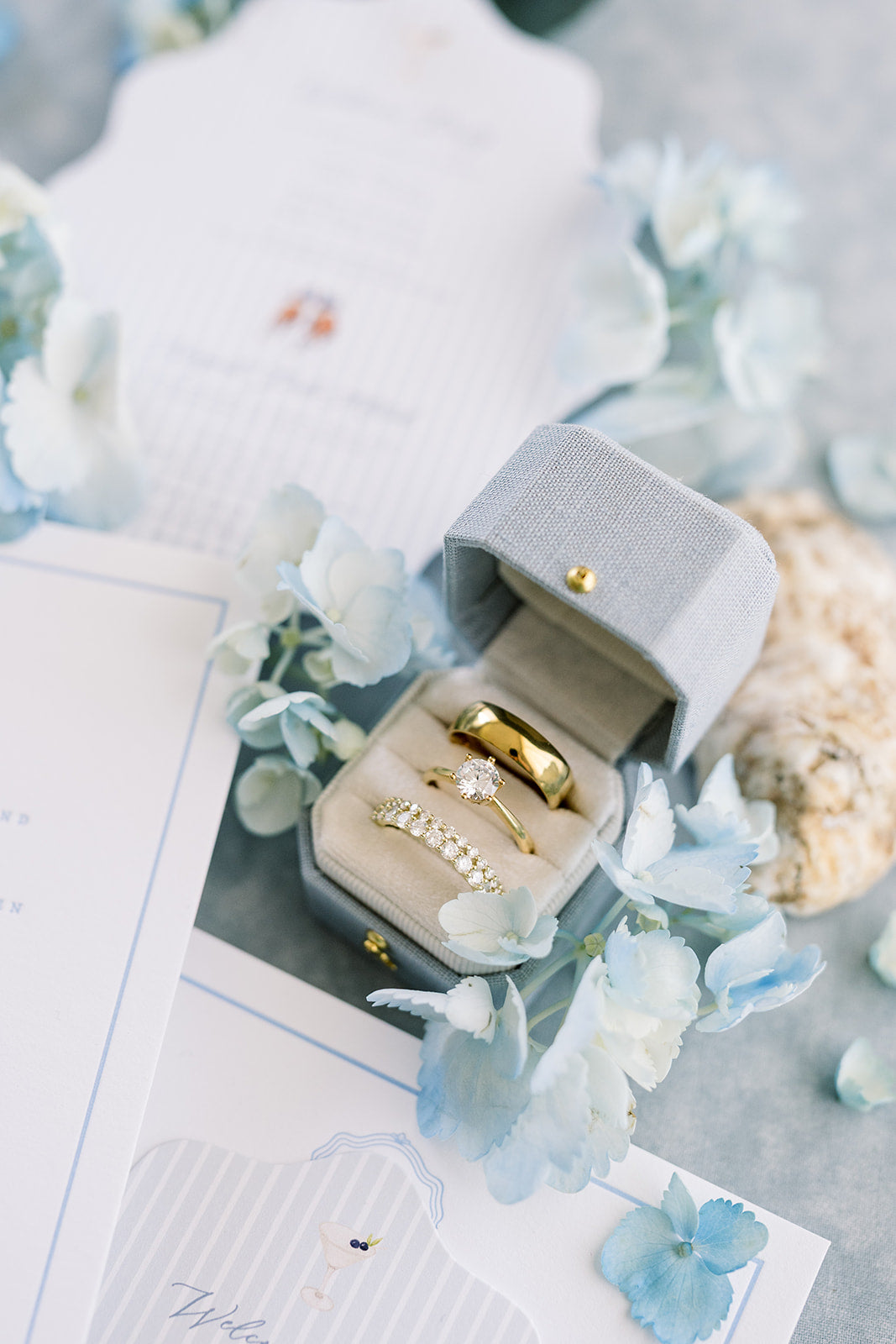 Hydrangea Radiant Legacy ring box open with rings beside blue florals