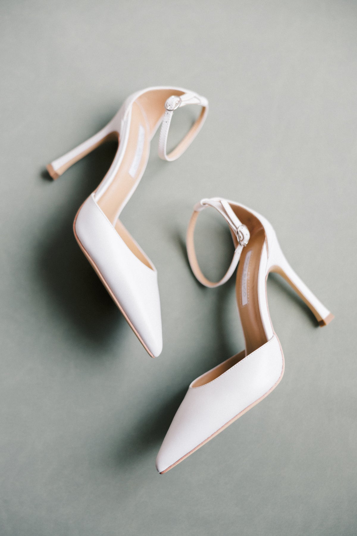 White bridal heels on a Sage green suede styling mat