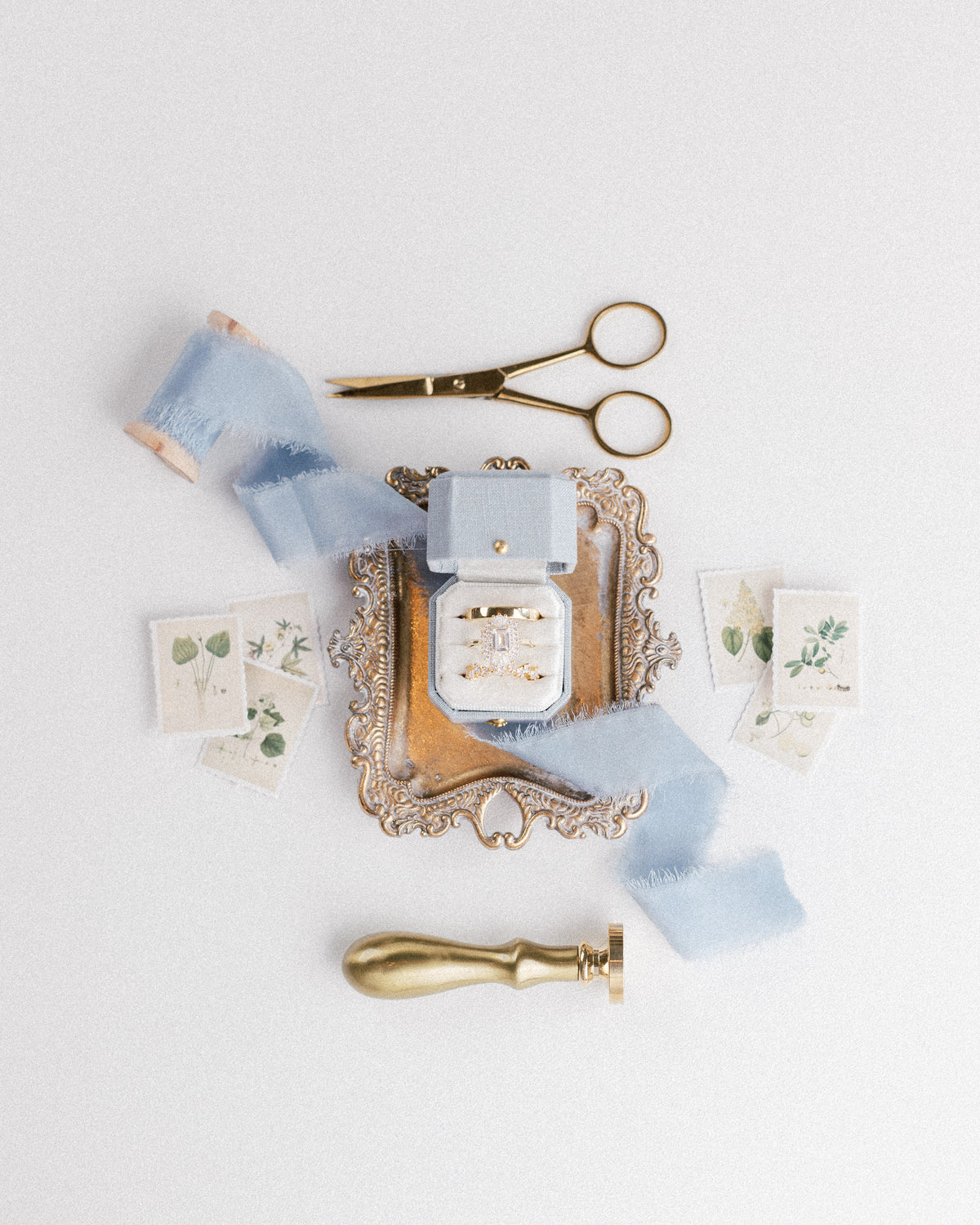 Gold-tone scissors and blue ribbon with a Hydrangea Radiant Legacy ring box