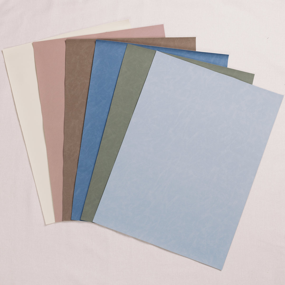 Suede styling mats in neutral and blue shades fanned out